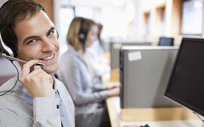 Operador telefÃ³nico en oficina con cubÃ­culos, sonriendo hacia cÃ¡mara.